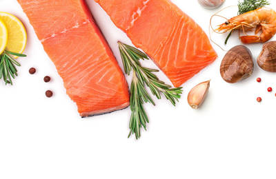 Two narrow slices of salmon fillets, a cooked whole shrimp, and two clams with lemon wedges, rosemary, and garlic cloves
