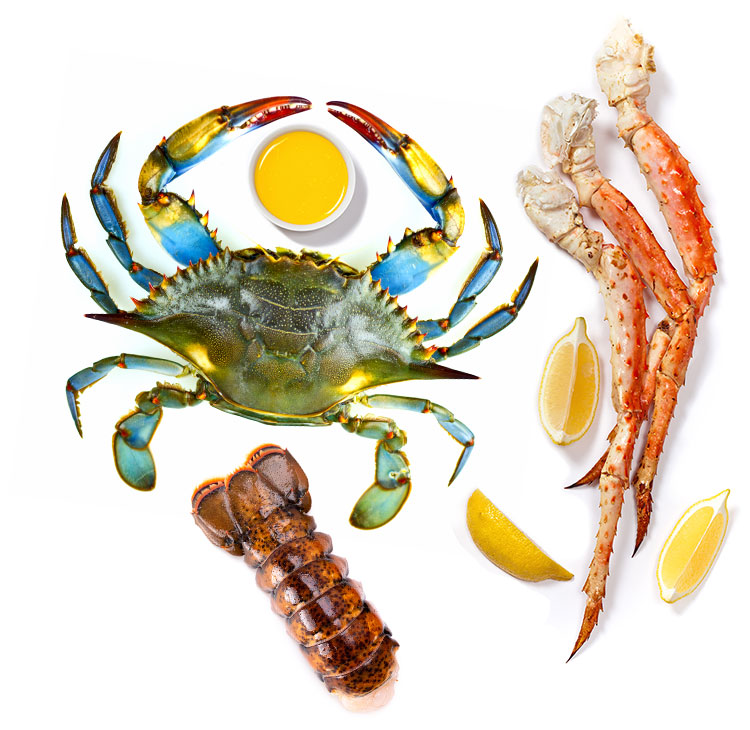 Three cooked crab legs, a lobster tail, and a whole blue crab with three lemon wedges and a dish full of melted butter
